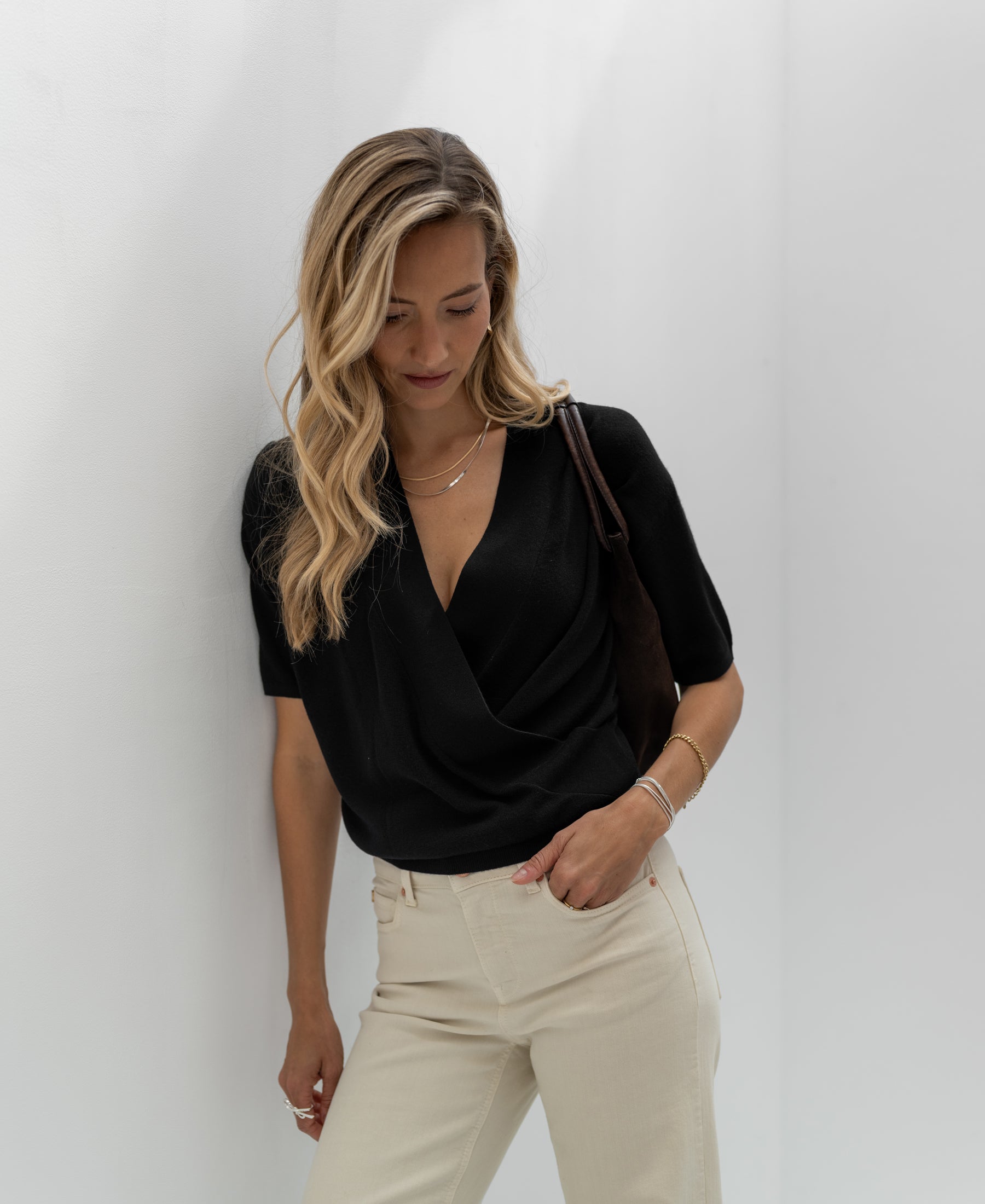 A woman wearing a PLEIN PUBLIQUE black wrap sweater.