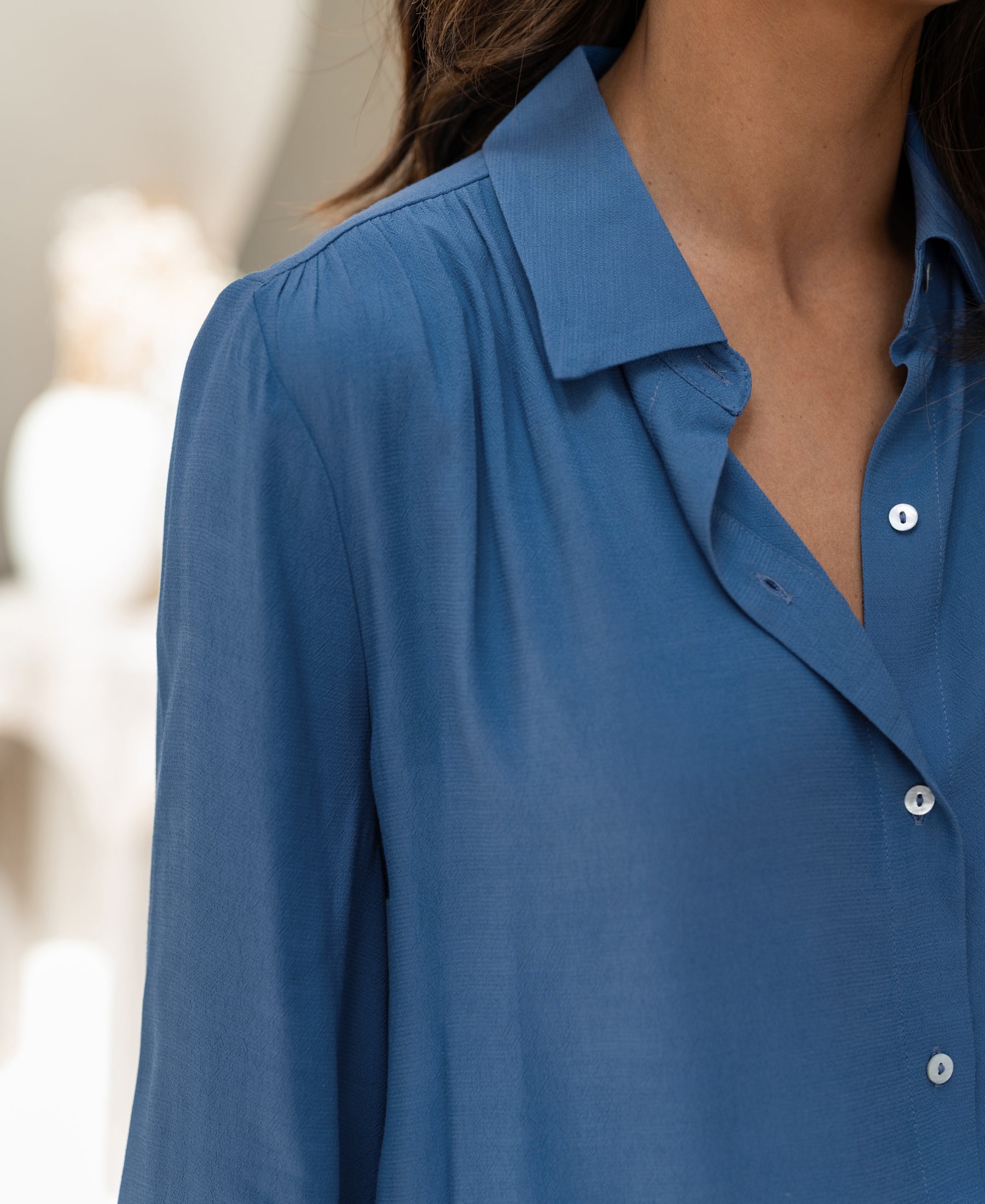 Blue PLEIN PUBLIQUE LA TROYES blouse with pleated cuffs, shown from shoulders to mid-chest.