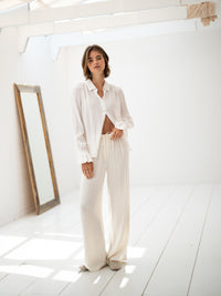 Loose white LA TROYES blouse by PLEIN PUBLIQUE shown in a bright, minimal room with a mirror.