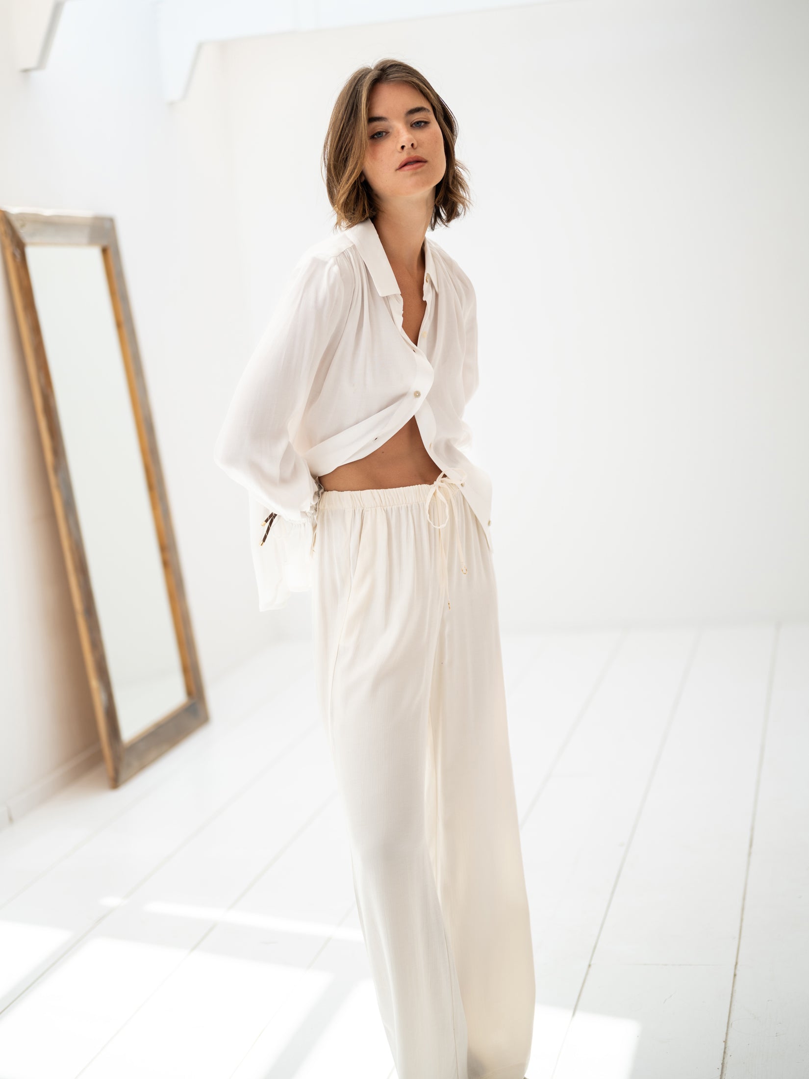 Cream elastic waist pants displayed in a bright room with a mirror.