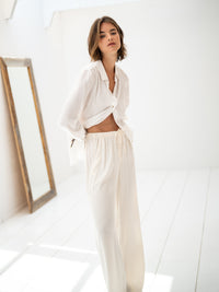 Cream elastic waist pants displayed in a bright room with a mirror.