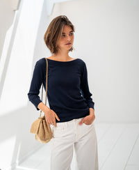 Woman wearing a navy blue Tencel-silk boat neck sweater.