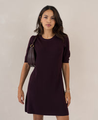 Aubergine merino wool dress in a shift style, shown on a woman against a light background.