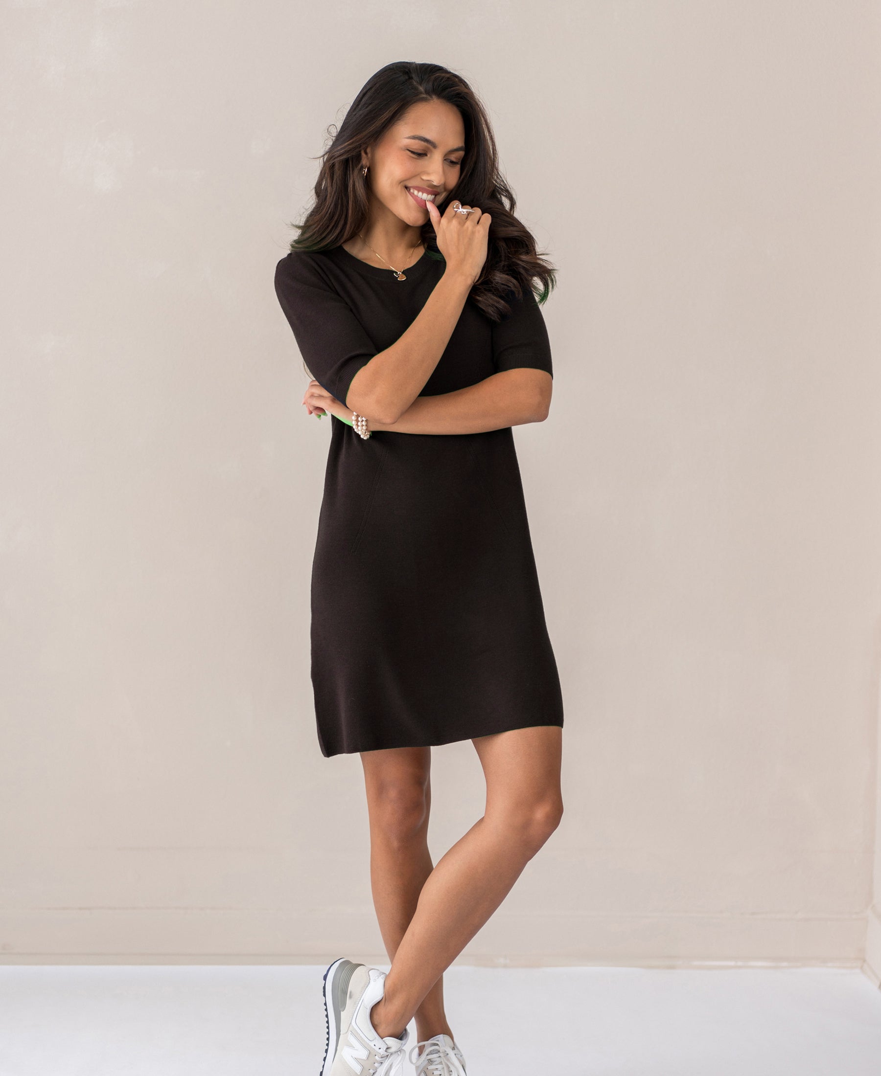 Woman wearing the Plein Publique merino wool dress LA TWIGGY in chocolate color, standing against a beige backdrop.