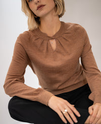 PLEIN PUBLIQUE LA TWIST merino wool sweater in chai tea color, shown on a model, arm resting on her knee.
