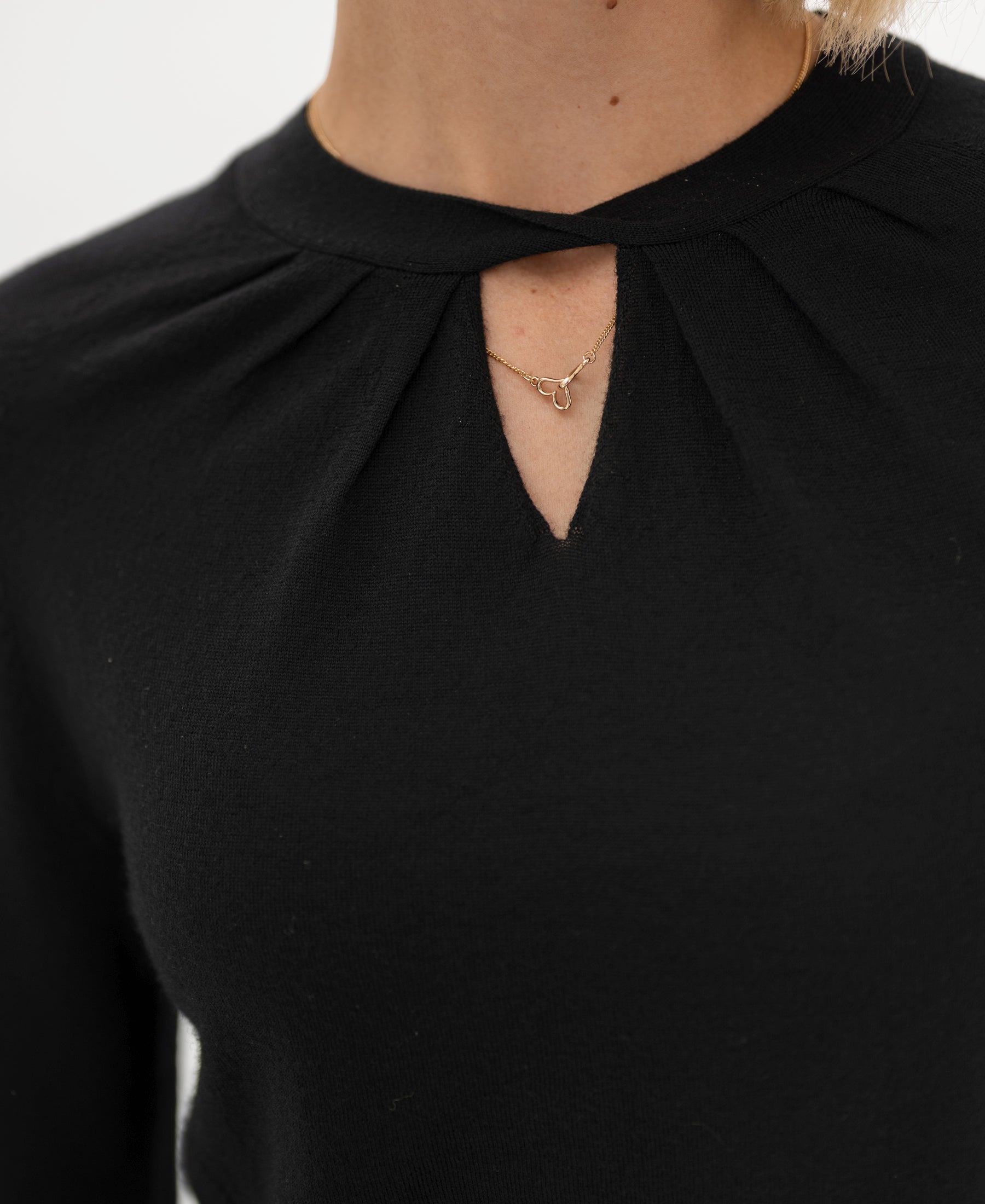 Close-up of a black merino wool twist sweater with a keyhole neckline.