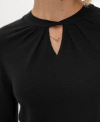 Close-up of a black merino wool twist sweater with a keyhole neckline.