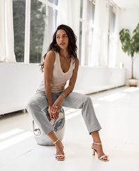 Woman wearing a luxe, soft butter-colored top sits on a stool in a modern, bright room.