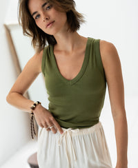 Woman wearing the Plein Publique Luxe & Soft LA VALE olive green top stands indoors, looking relaxed at the camera.