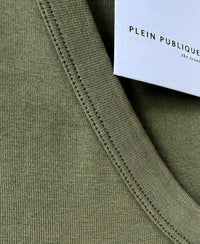 Close-up of luxe and soft olive green top collar with white PLEIN PUBLIQUE tag attached.