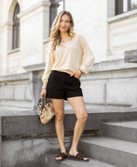 Woman wearing black LA MADDY shorts stands on stone steps.