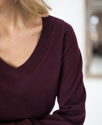 Merino wool V-neck sweater in Bordeaux red, shown from shoulders to mid-torso.