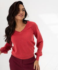PLEIN PUBLIQUE Merino wool V-neck sweater LA VILLE in red, shown on a model in a minimal room.