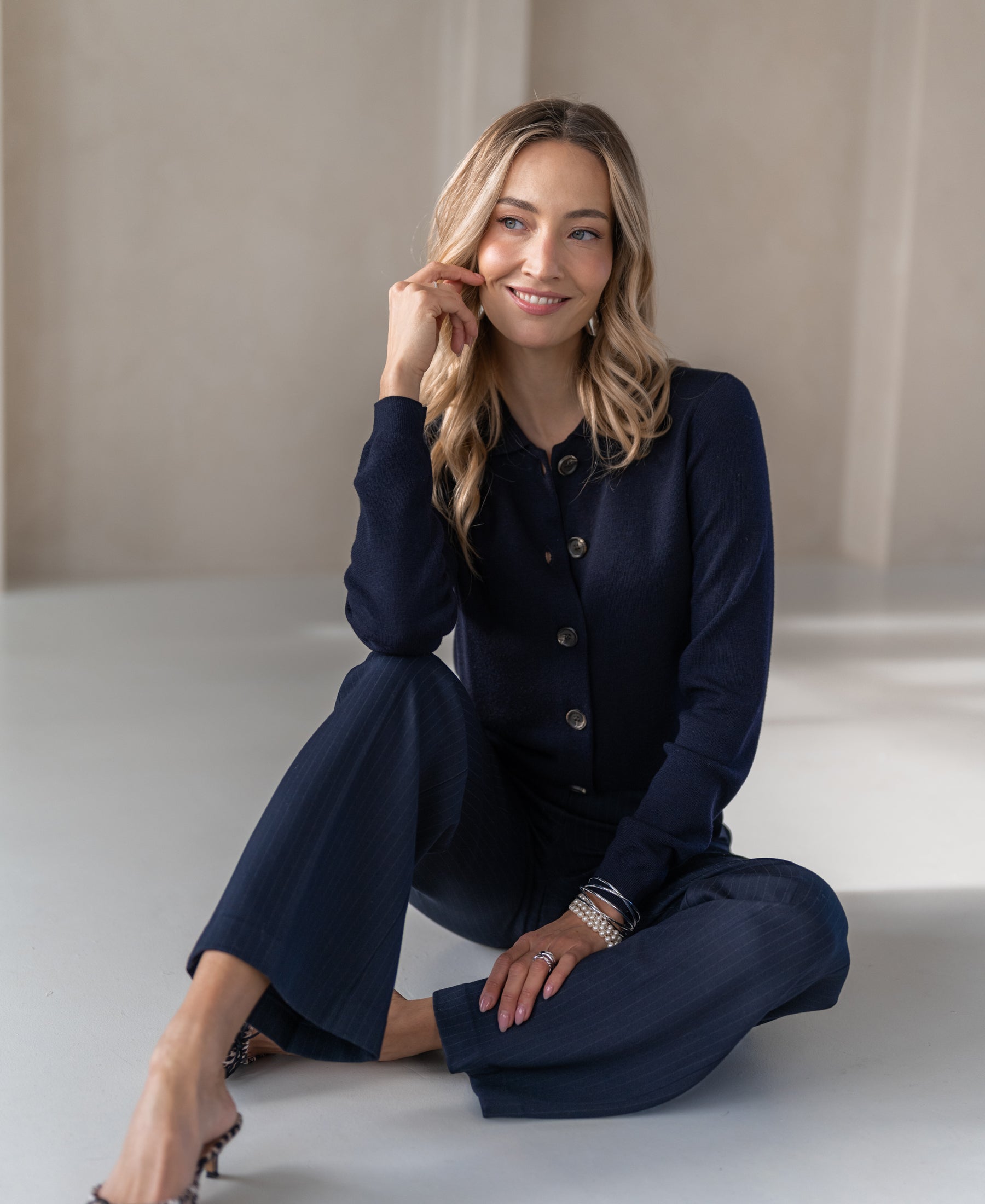 Navy blue knit vest with polo collar, shown on a model sitting on the floor.