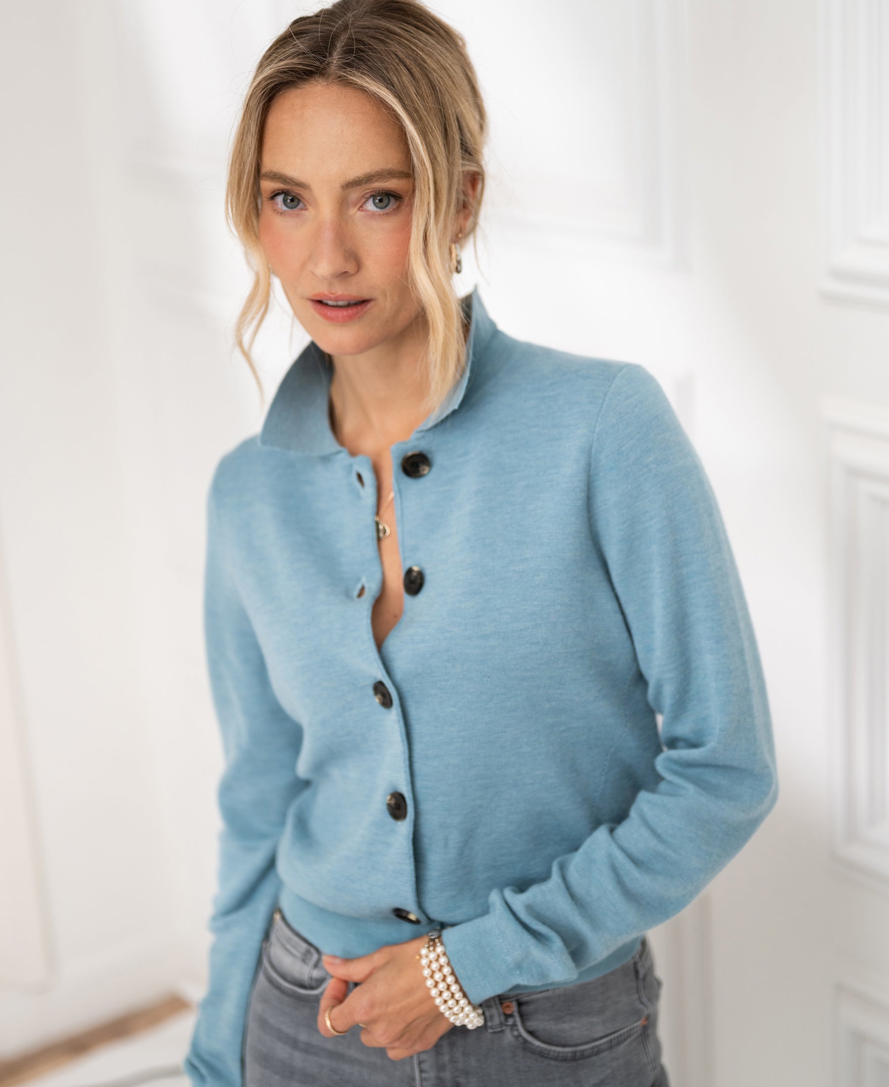 Woman wearing the PLEIN PUBLIQUE blue polo-collar knit vest, standing indoors.