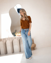 Woman wearing a PLEIN PUBLIQUE stretch short-sleeve LA VOICE Havana T-shirt in a minimalist room.