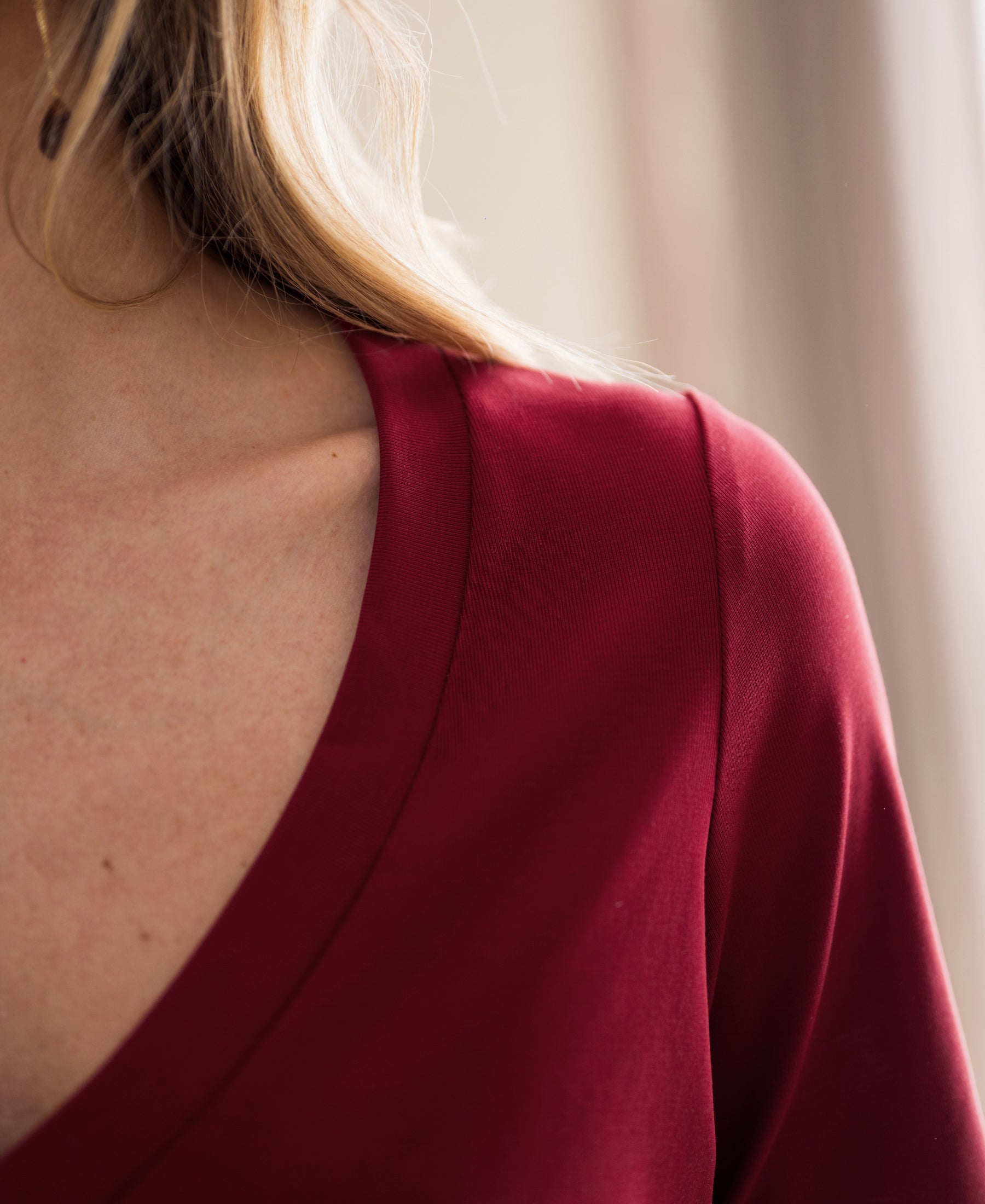 Close-up of a person wearing a PLEIN PUBLIQUE stretch short-sleeve T-shirt in chili red, showing shoulder and neck.