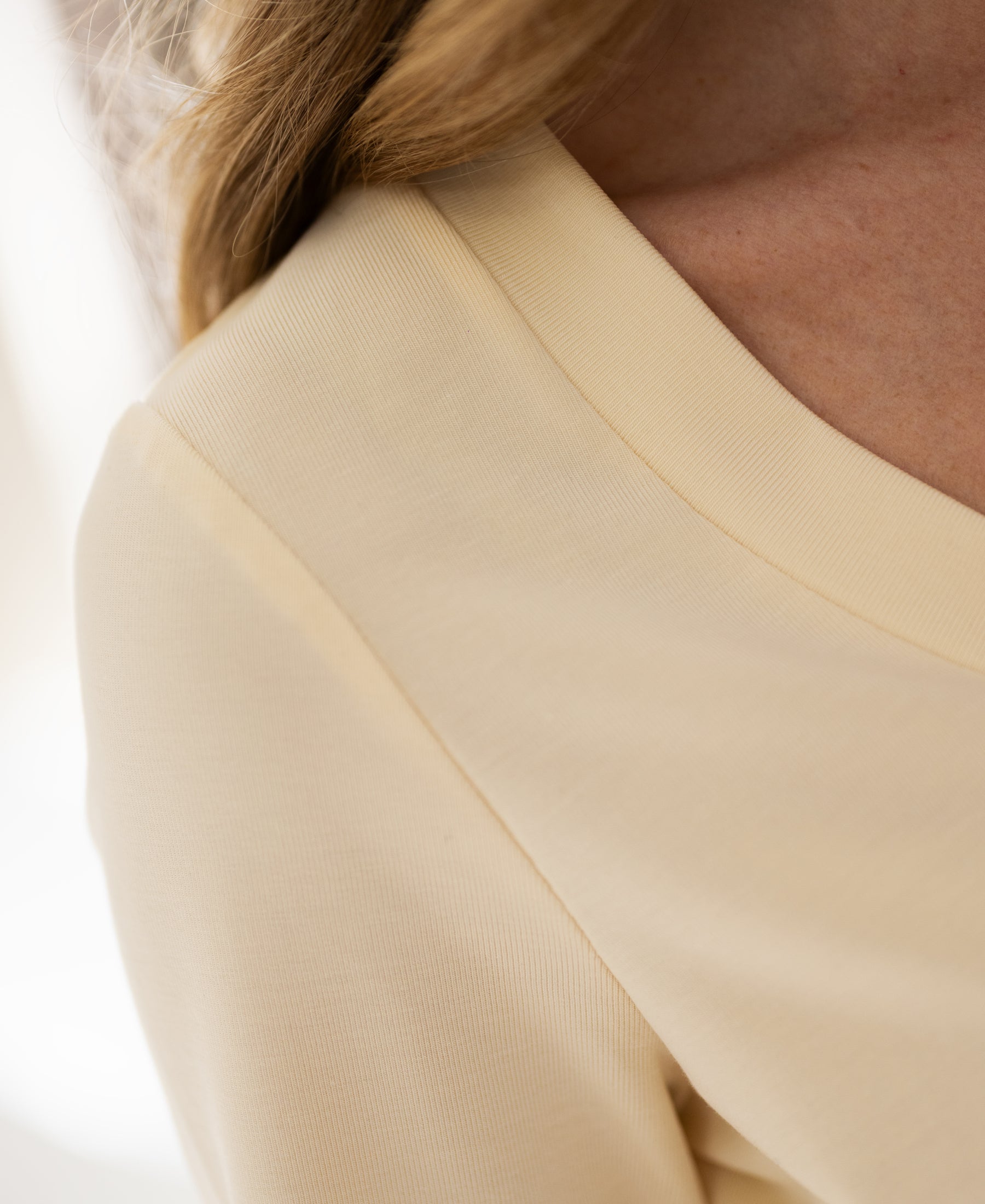 Close-up of a soft yellow stretch short-sleeve T-shirt, showing shoulder and neckline.