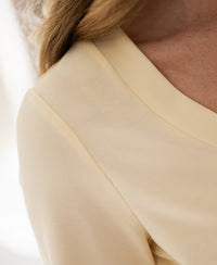 Close-up of a soft yellow stretch short-sleeve T-shirt, showing shoulder and neckline.