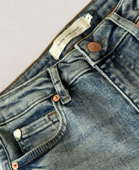 Close-up of vintage wash flare jeans with stretch waistband, button, and front pocket by Plein Publique.