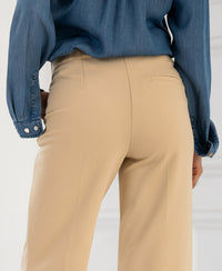 Back view of person wearing beige LA WENDE pants against a light background.