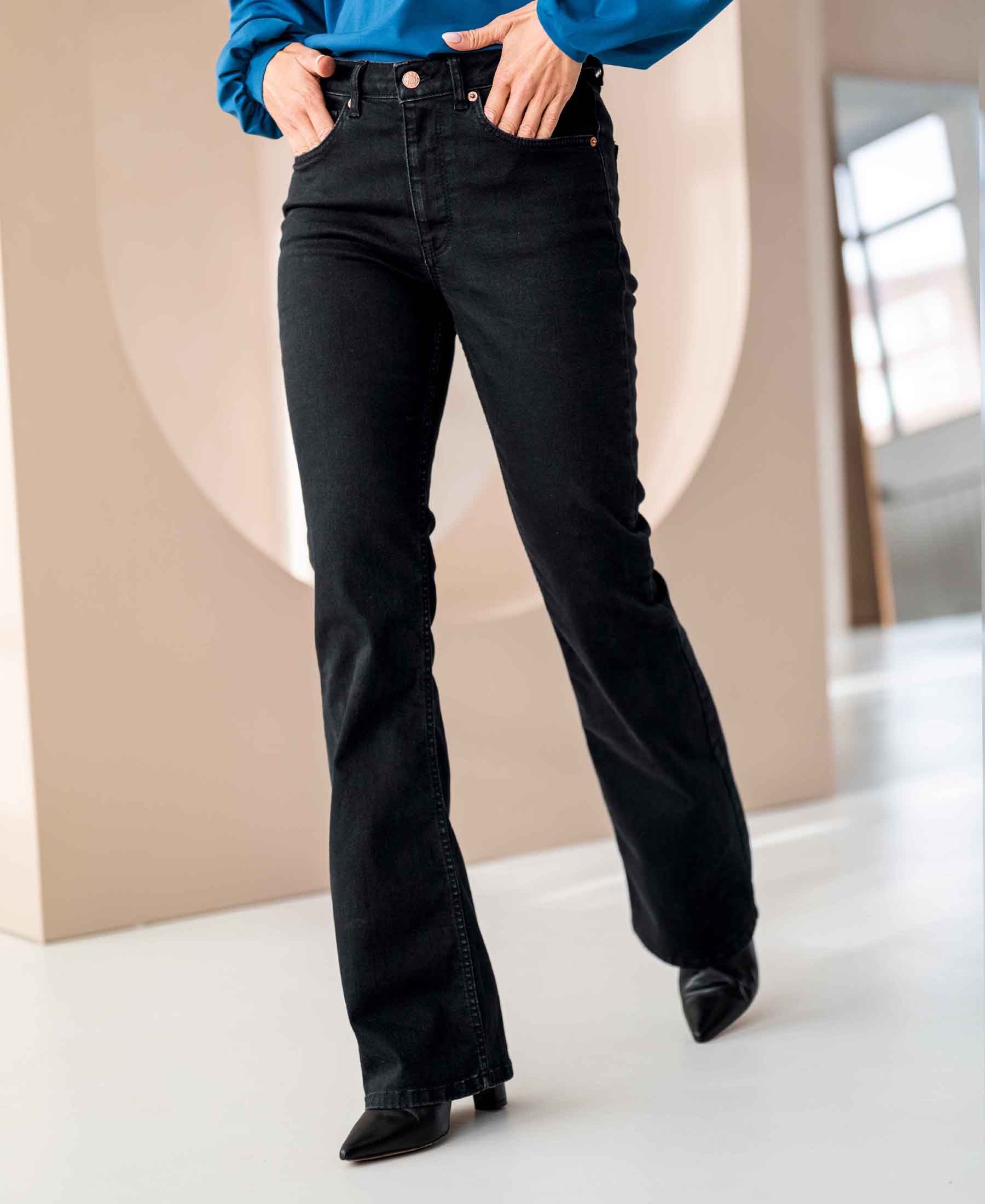 Person wearing black denim flared jeans.