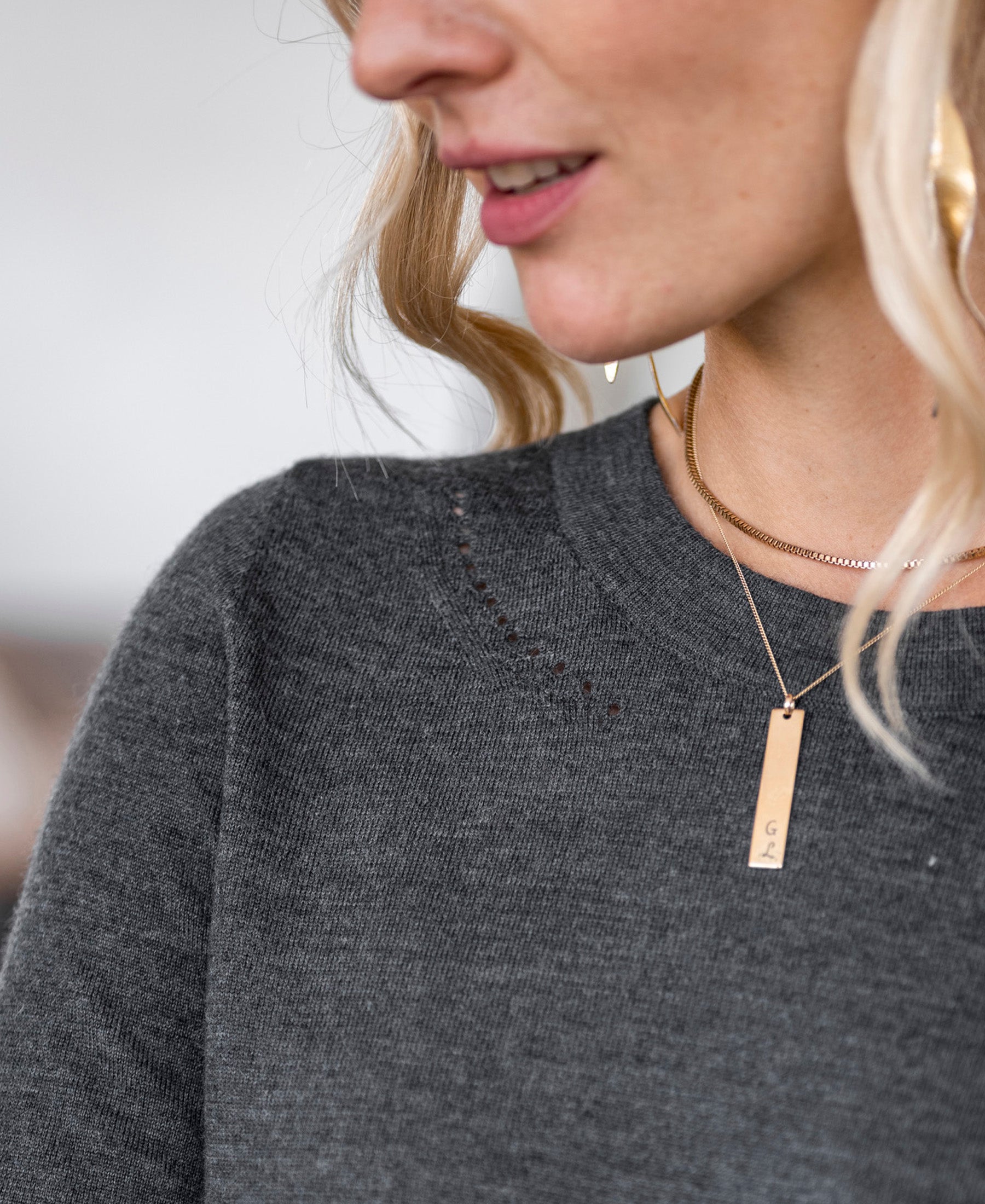 Woman wearing PLEIN PUBLIQUE merino wool sweater LA MARIS in anthracite-gold, side view.