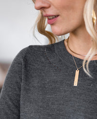 Woman wearing PLEIN PUBLIQUE merino wool sweater LA MARIS in anthracite-gold, side view.