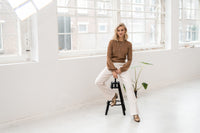 PLEIN PUBLIQUE's Merino wool LA COEUR Chai Tea sweater shown on a model in a bright, airy room.