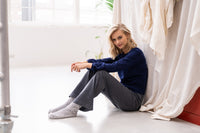 Grey knitted pants by PLEIN PUBLIQUE, LE LOURDES style, shown on a seated model in a bright room.