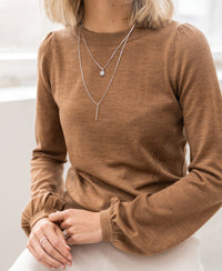 Woman wearing a Plein Publique merino wool La Coeur Chai Tea sweater, hands on lap.