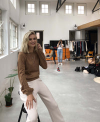 Woman wearing a PLEIN PUBLIQUE merino wool LA COEUR Chai Tea sweater, in a bright studio.