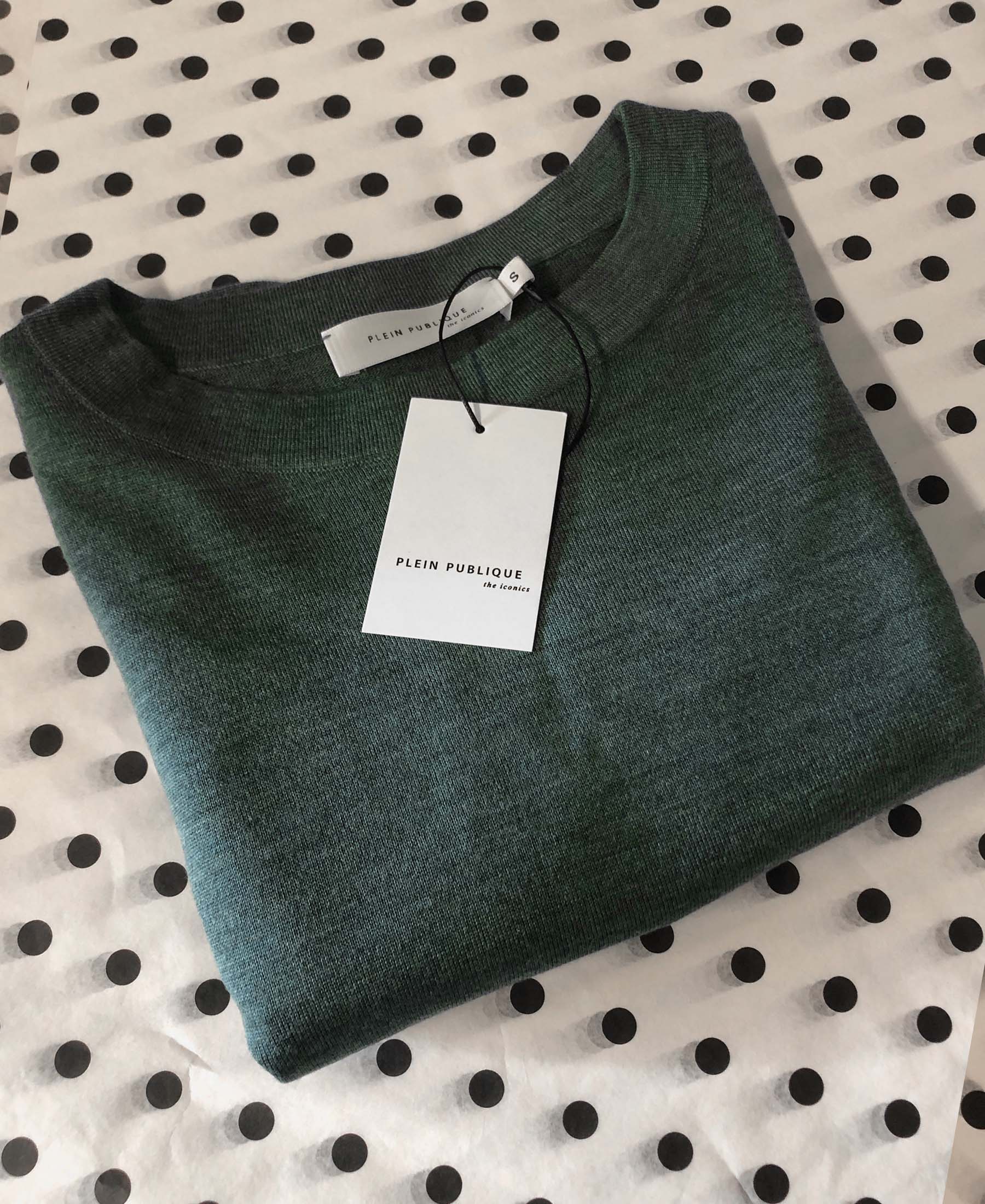 The LA COEUR Greenish merino sweater by PLEIN PUBLIQUE, finely knit with balloon sleeves and label, folded on white with dots.