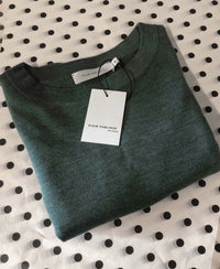 The LA COEUR Greenish merino sweater by PLEIN PUBLIQUE, finely knit with balloon sleeves and label, folded on white with dots.