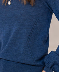 Close-up of indigo blue merino wool sweater with balloon sleeves, side pocket, and pearl accents.