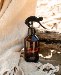 A PLEIN PUBLIQUE clothing fragrance spray bottle on beige cloth.