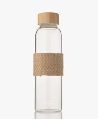 Glass water bottle with bamboo lid from PLEIN PUBLIC, made of durable borosilicate glass with a beige fabric strap.