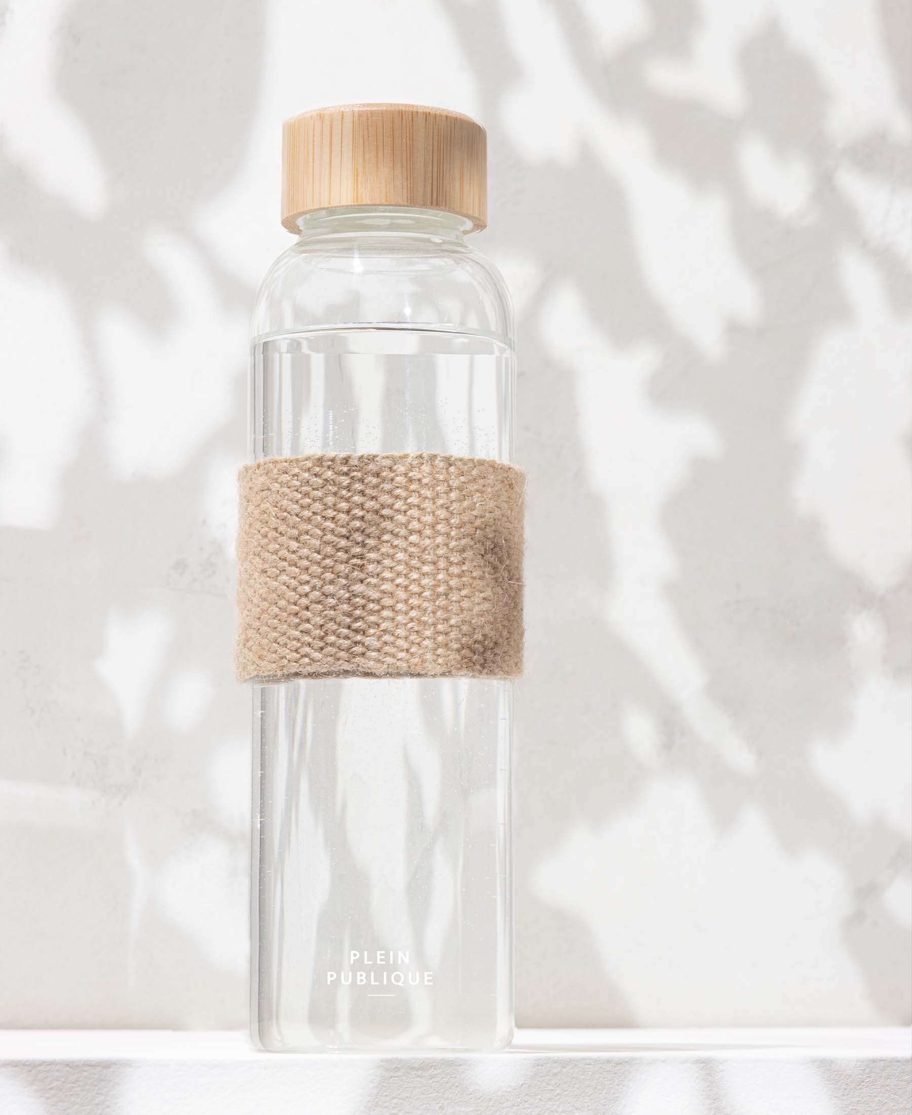 Glass water bottle with bamboo lid from PLEIN PUBLIQUE on a white background.
