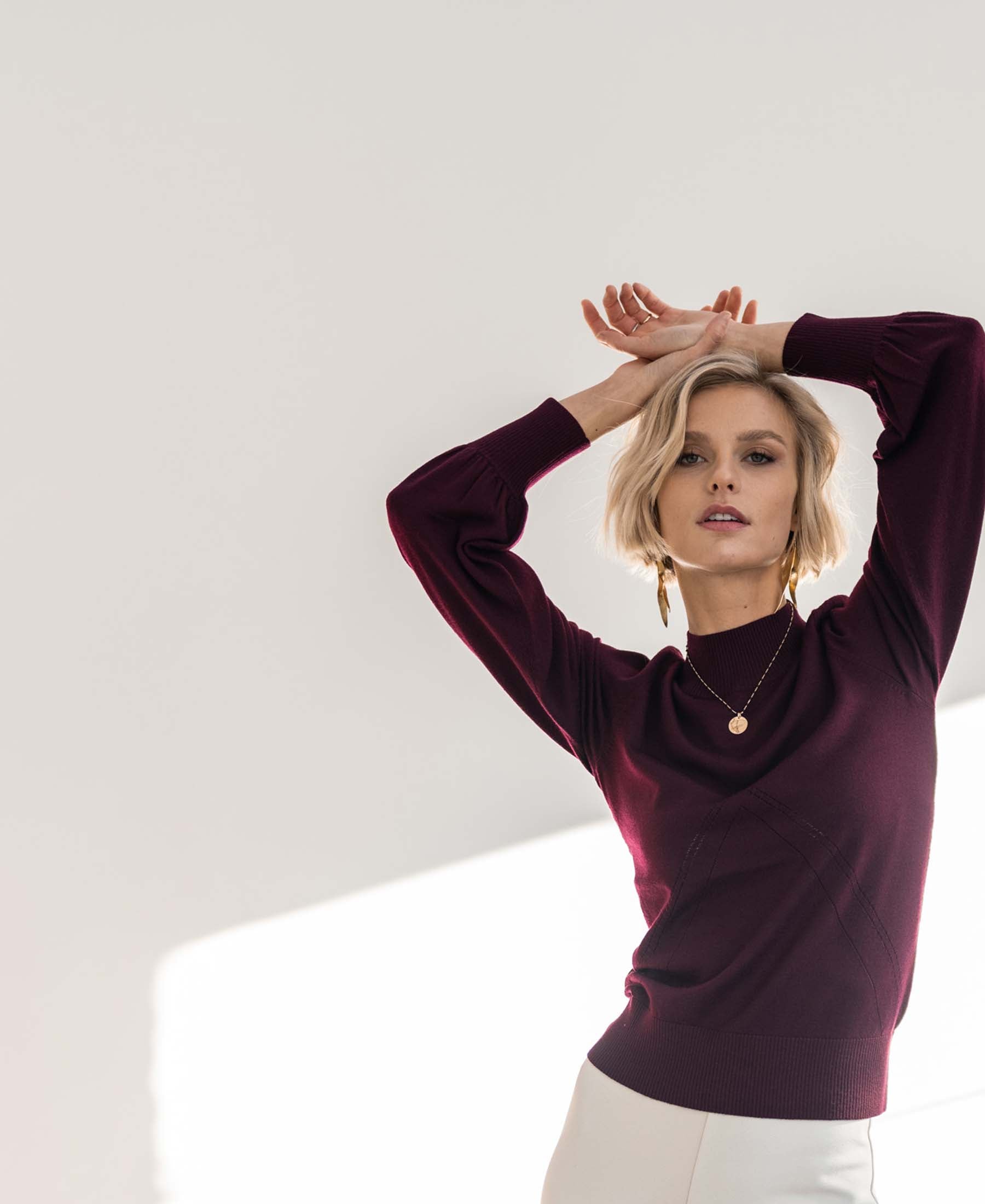 Woman wearing a burgundy turtleneck sweater with balloon sleeves.