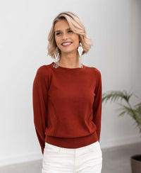 Woman wearing the LA COEUR Rosewood Merino wool sweater by PLEIN PUBLIQUE; plant in background.