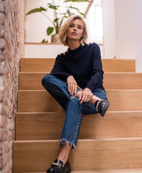 Woman with short blonde hair wears a dark blue LA CLIQUE Merino wool sweater by PLEIN PUBLIQUE.
