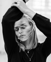Black and white photo of a woman wearing the black merino wool sweater, arms raised, eyes closed.
