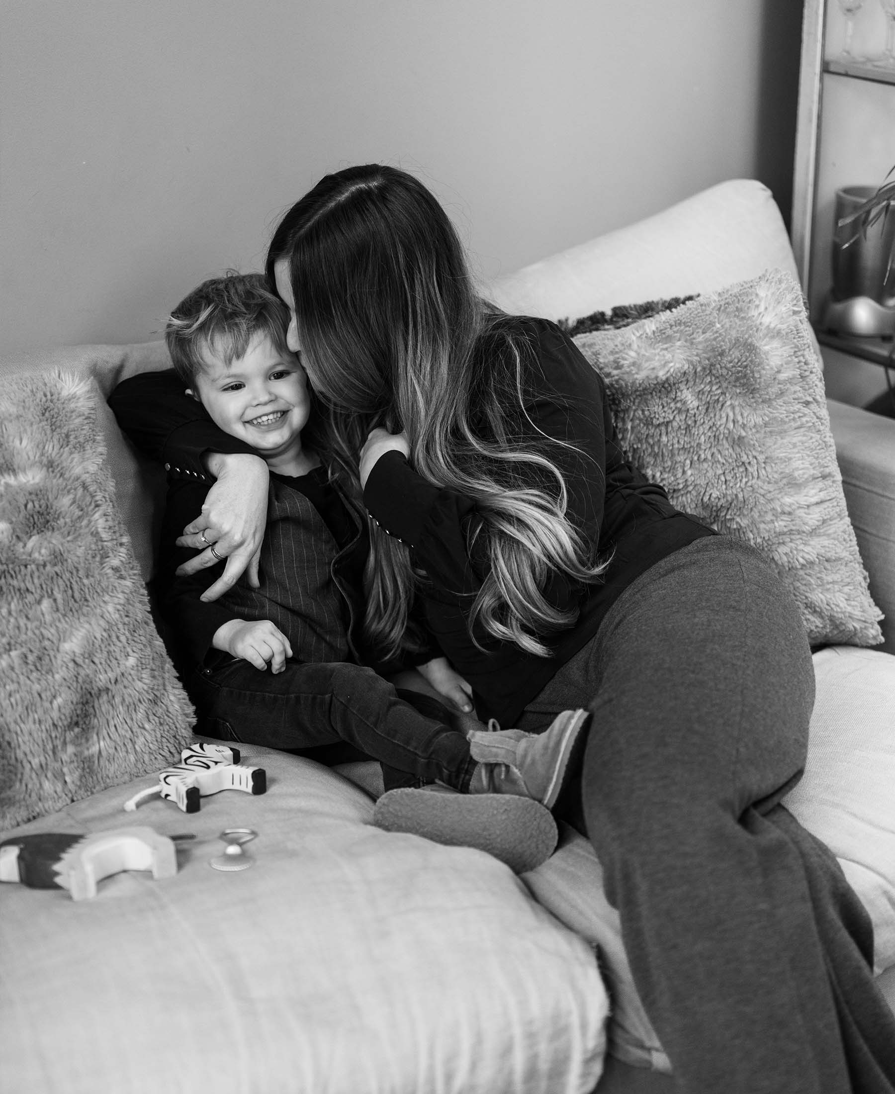 Woman wears anthracite knitted trousers as she sits on a couch.