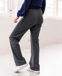 Person wearing anthracite knit trousers in a minimal room.