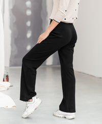 Black knit trousers LE LOURDES by PLEIN PUBLIQUE, shown indoors with one leg bent.