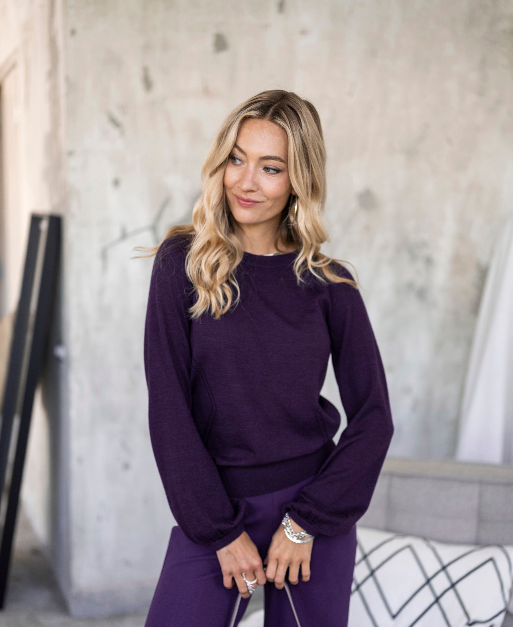 Dark violet LA COEUR sweater by PLEIN PUBLIQUE, shown indoors against a gray textured wall.
