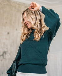 Dark green turtleneck sweater in a relaxed fit shown indoors.