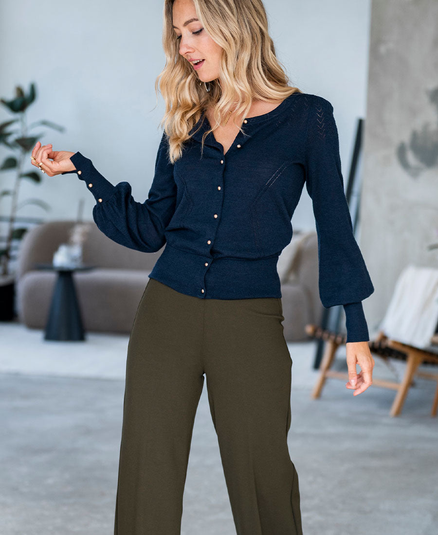 Woman wears the PLEIN PUBLIQUE LA FRAGANCE Navy-Gold Cardigan indoors.